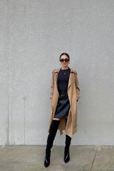 a lady in a black top, a black skirt and a brown unisex coat